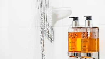 Twee flessen Aqua Viva shampoo en conditioner, en douche- en badgel, naast een douchekop waar water uitstroomt.