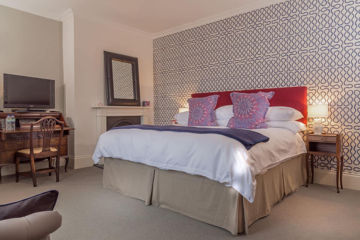 Quarto de hotel com cama, televisão, escrivaninha e cadeira.