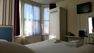 A hotel room with a bed, a wardrobe, a television, and a window with curtains.
