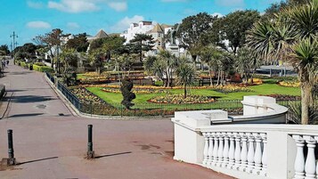A landscaped garden with a fountain, palm trees, and a variety of colorful flowers.