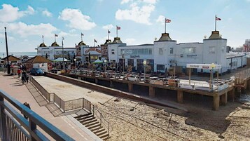 A boardwalk with shops and a pier, featuring a white building with multiple flags and a sign for 'Boardwalk'.