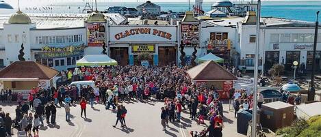 Une rue animée où une foule s’est rassemblée devant un bâtiment portant l’inscription « CLACTON PIER ».