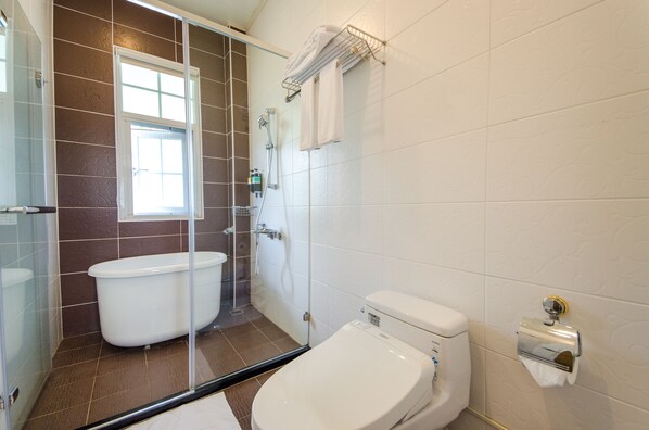 Un baño con ducha envuelta en vidrio, inodoro blanco y bañera con mampara de vidrio.