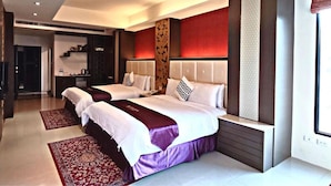 A modern hotel room with two beds, a sitting area, and a view of the city.