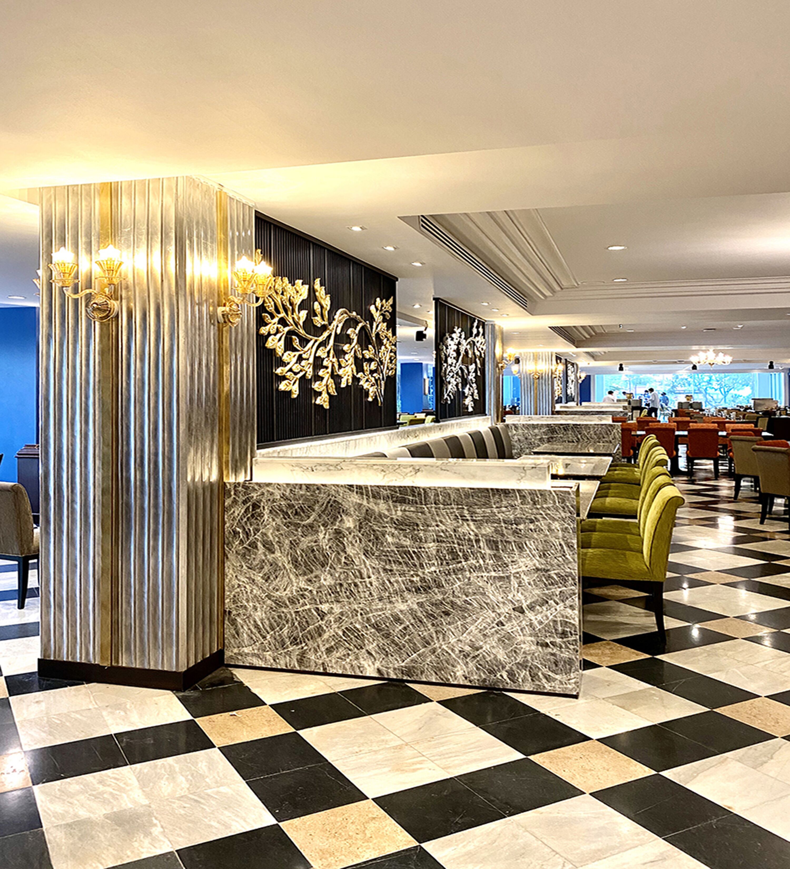 A hotel lobby with a check-in counter, seating area, and a patterned floor.