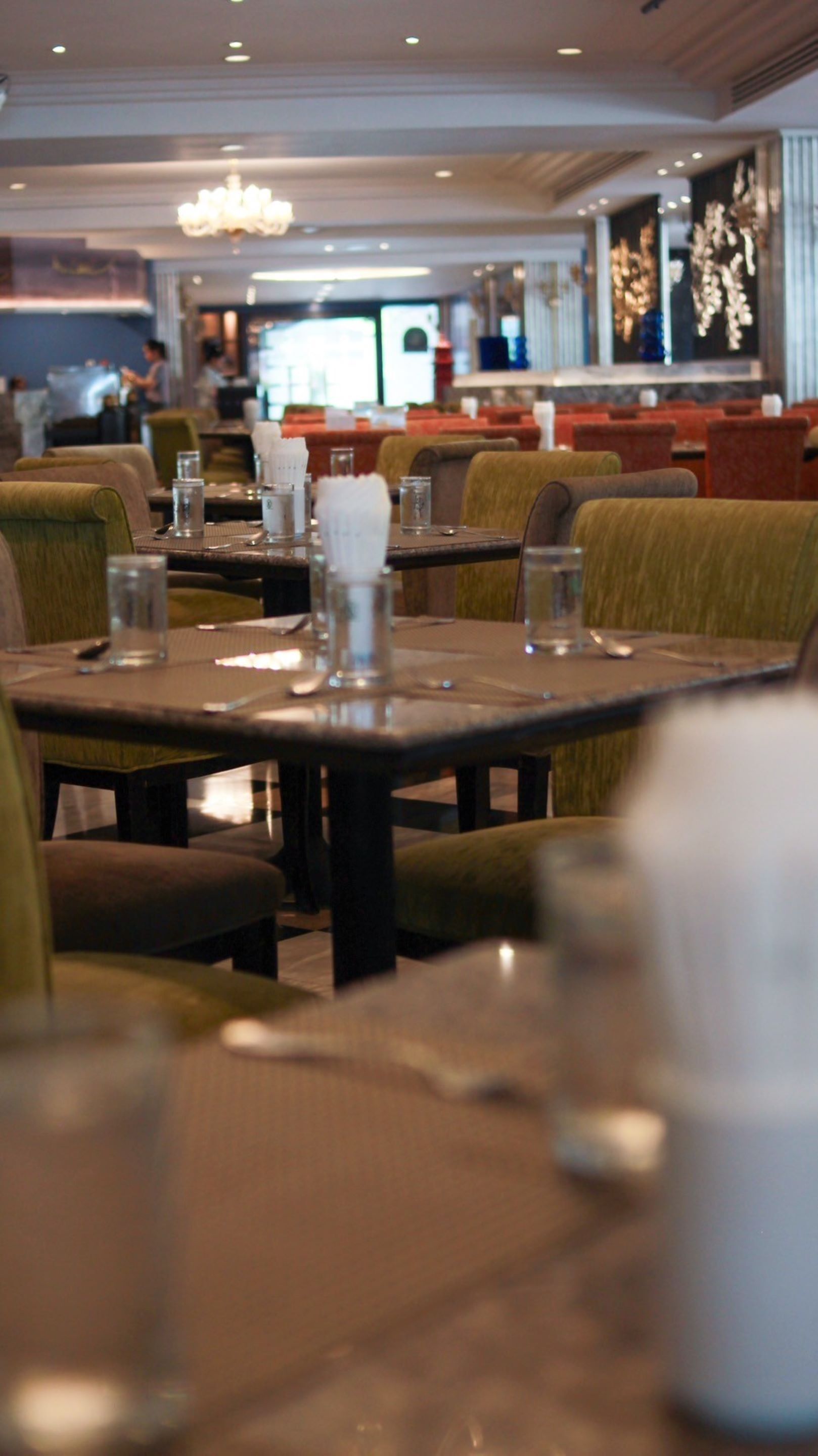 A restaurant interior with tables set for dining, chairs, and a chandelier.