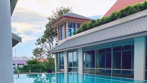Un edificio moderno con piscina, ventanas amplias y techo rojo.