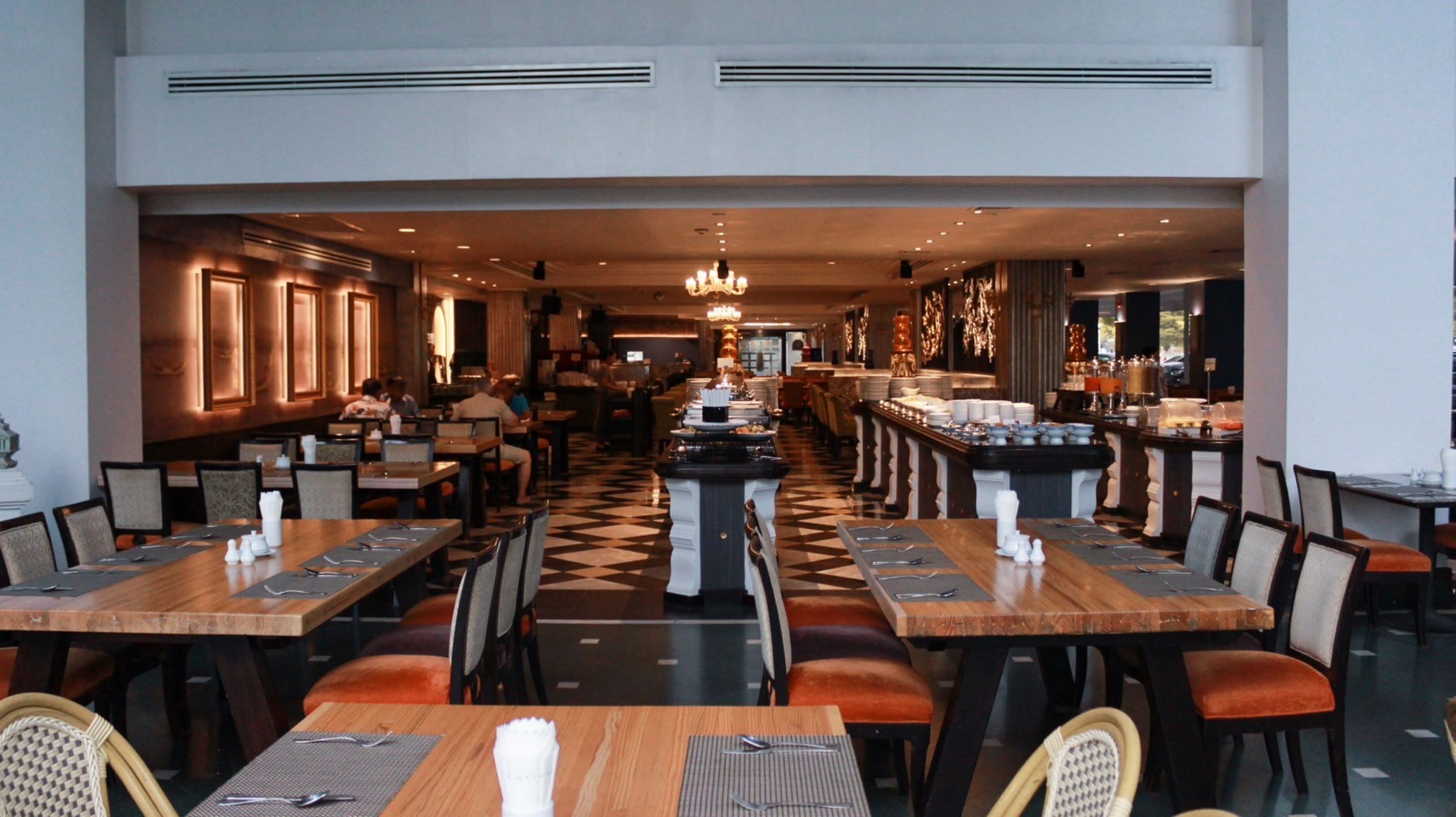 A restaurant with long communal tables, individual booths, and a buffet area.