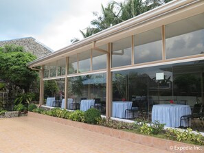 Un restaurant doté d’une terrasse, de grandes fenêtres et d’un mur en pierre servant de décor.