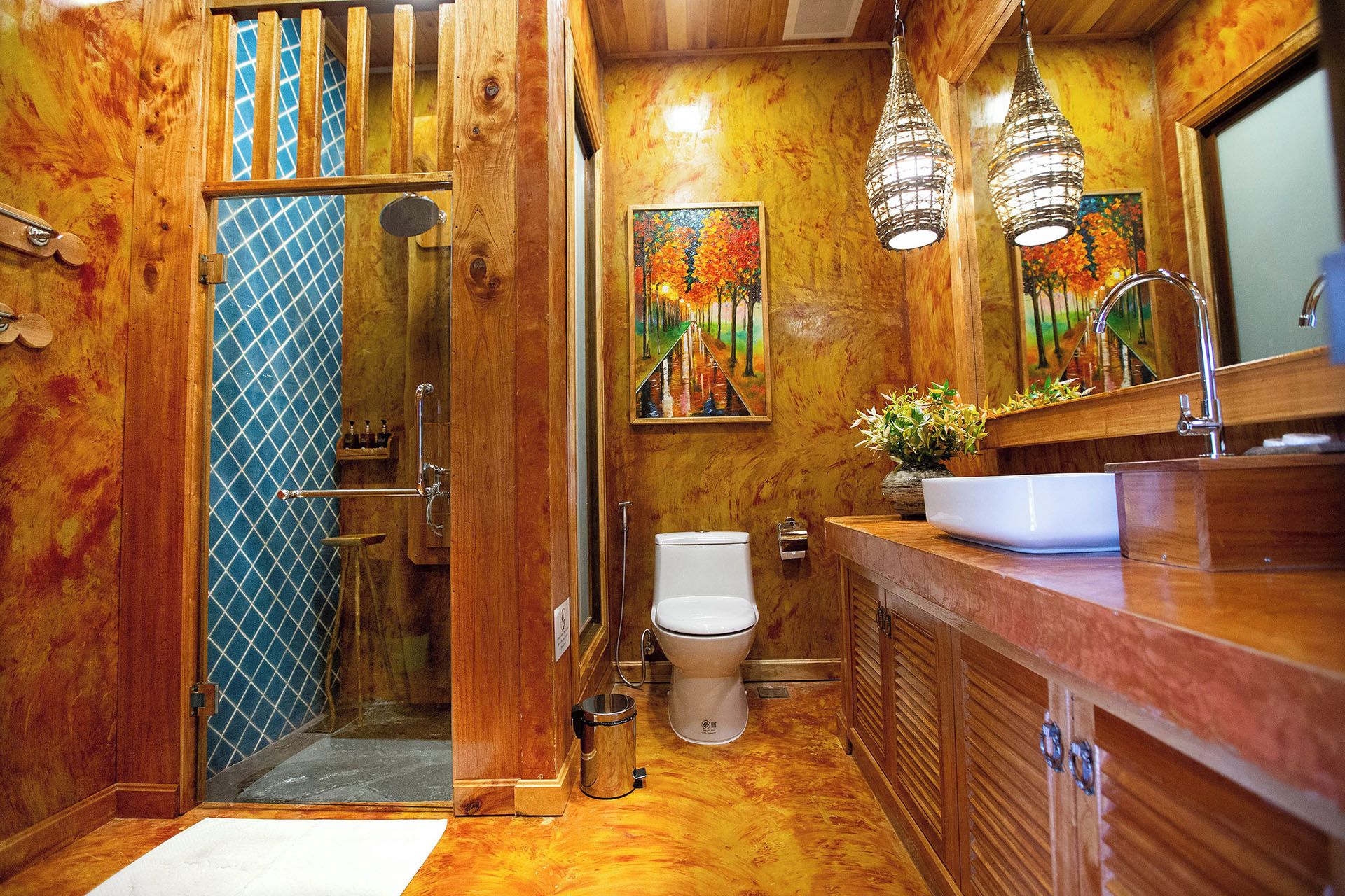 A bathroom with wooden walls, a toilet, a sink, and two hanging pendant lights.