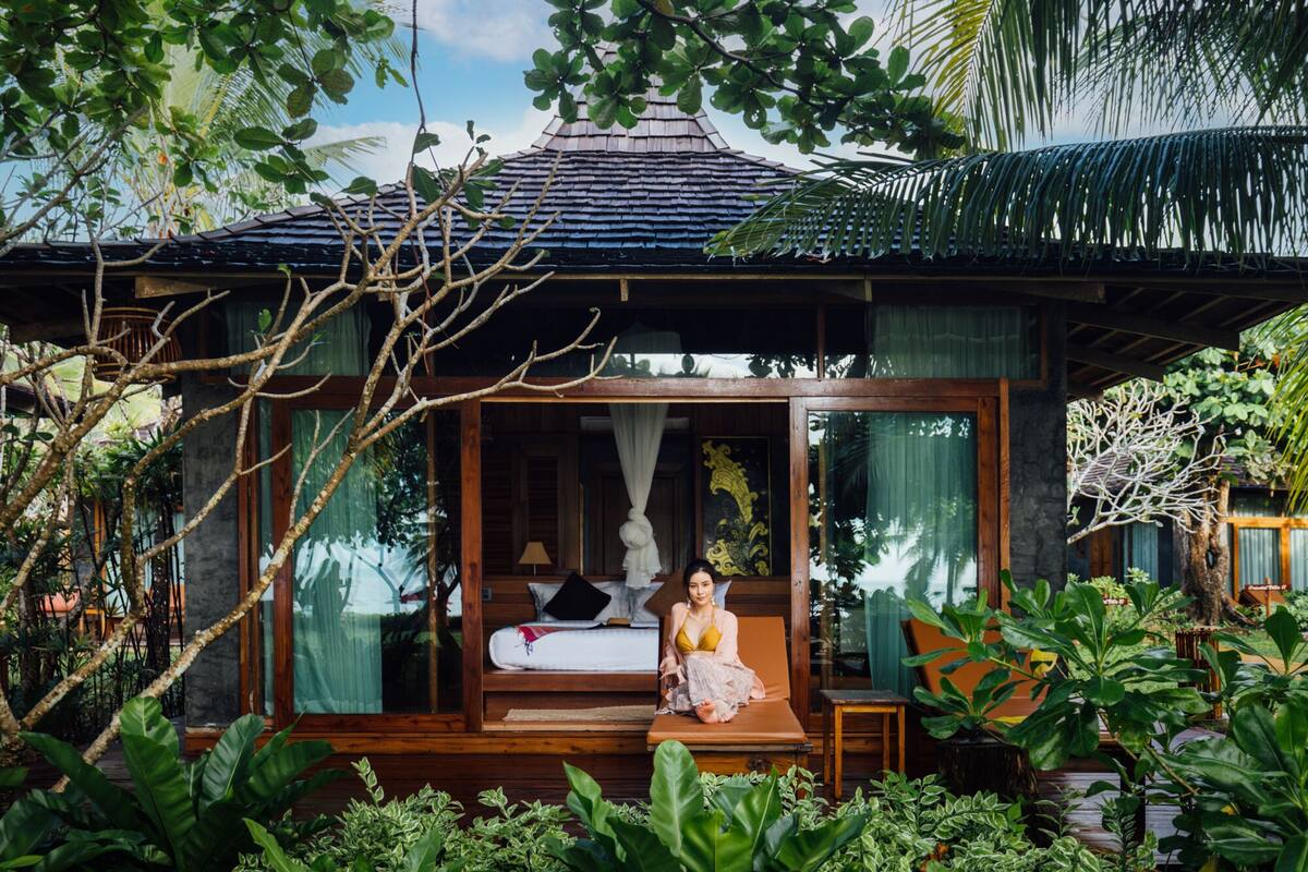 A wooden structure with a bed, a sitting area, and a window with curtains.