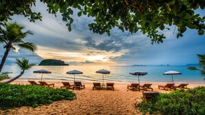 A beach with lounge chairs and umbrellas, a sandy shore, and a view of the sea and distant islands. - Andalay Beach Resort Koh Libong (Ko Libong)