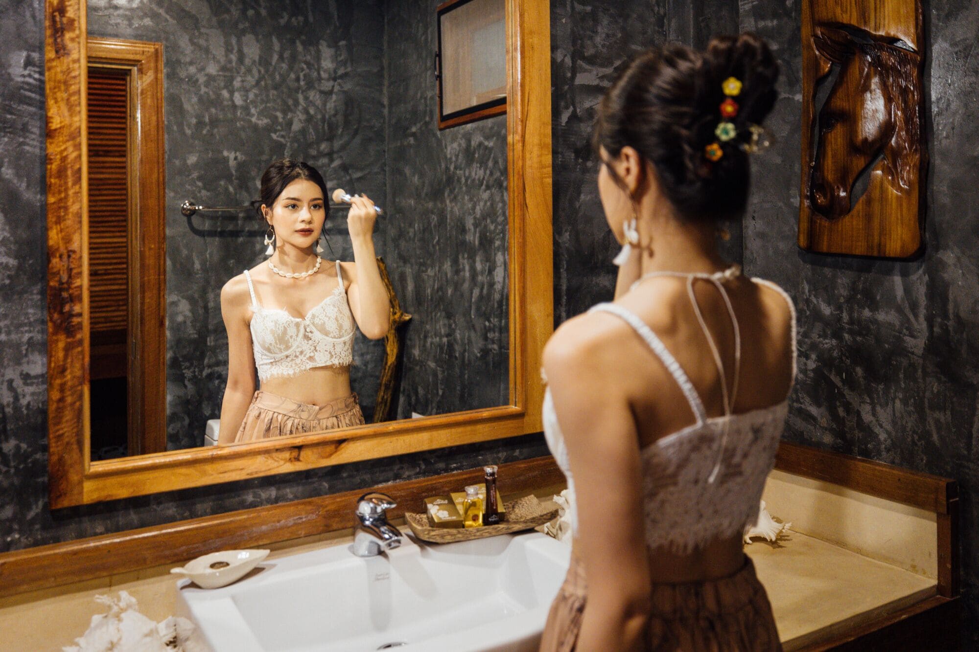 A bathroom with a large mirror, a sink, and toiletries on the counter.