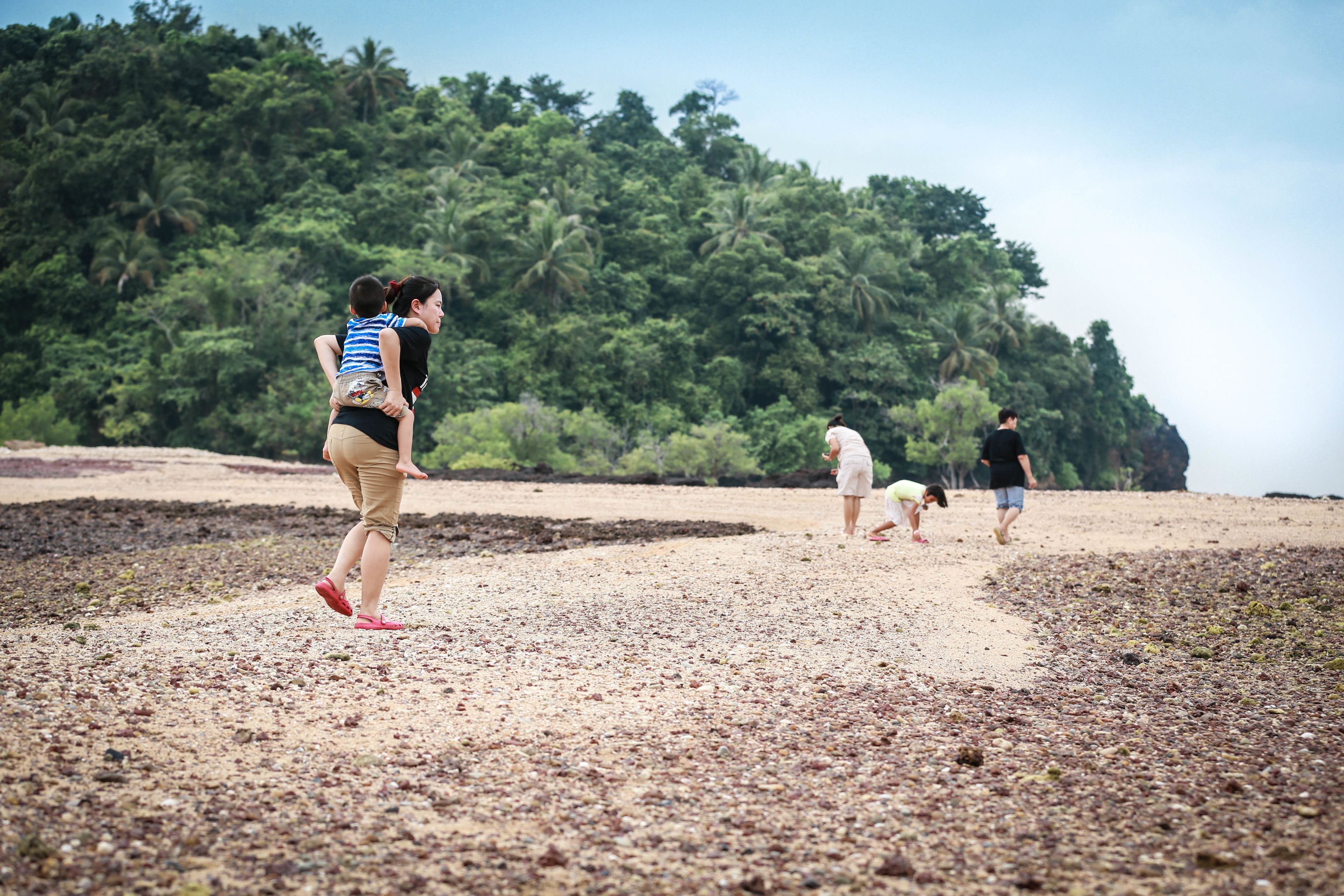 A beach scene with people walking and playing.