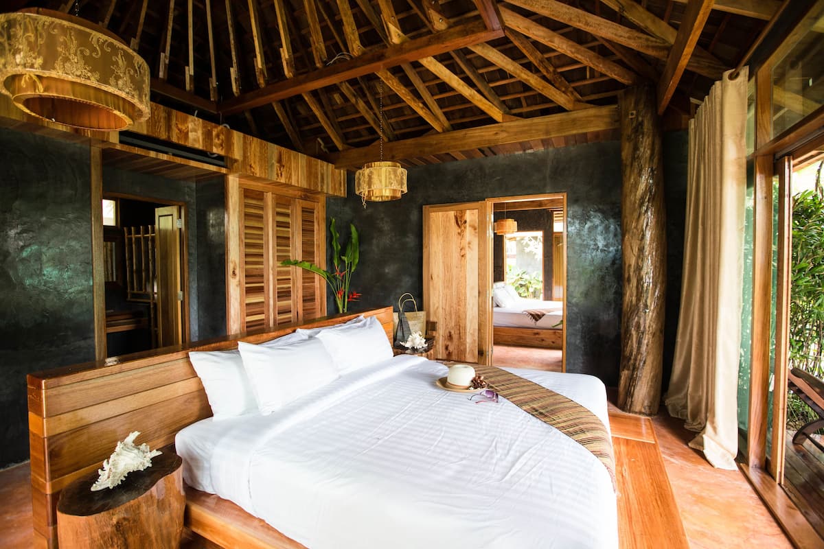 A spacious bedroom with a large bed, wooden headboard, and a ceiling fan.