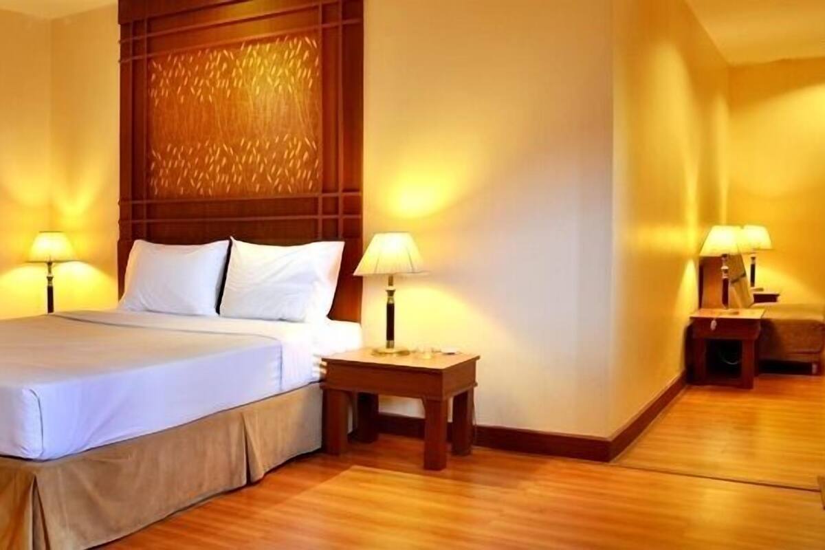 A hotel room with a large bed, two bedside tables with lamps, and a wooden headboard.