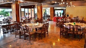 A spacious restaurant with multiple round tables and chairs, large windows, and a stage for events. - Friendlytel Hotel (Hat Yai)