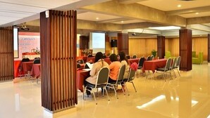 A conference room with a presentation screen, round tables, and attendees seated. - Friendlytel Hotel (Hat Yai)
