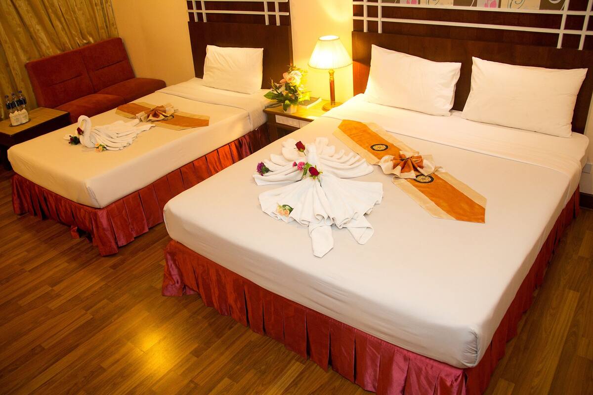 A hotel room with two beds, each with neatly folded towels and a bouquet of flowers.