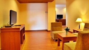 A hotel room with a wooden floor, a desk with a television, a sofa, and a lamp. - Friendlytel Hotel (Hat Yai)