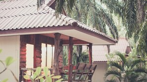 A wooden cabin with a corrugated metal roof, surrounded by palm trees. - Palm Garden Resort (Sikao)