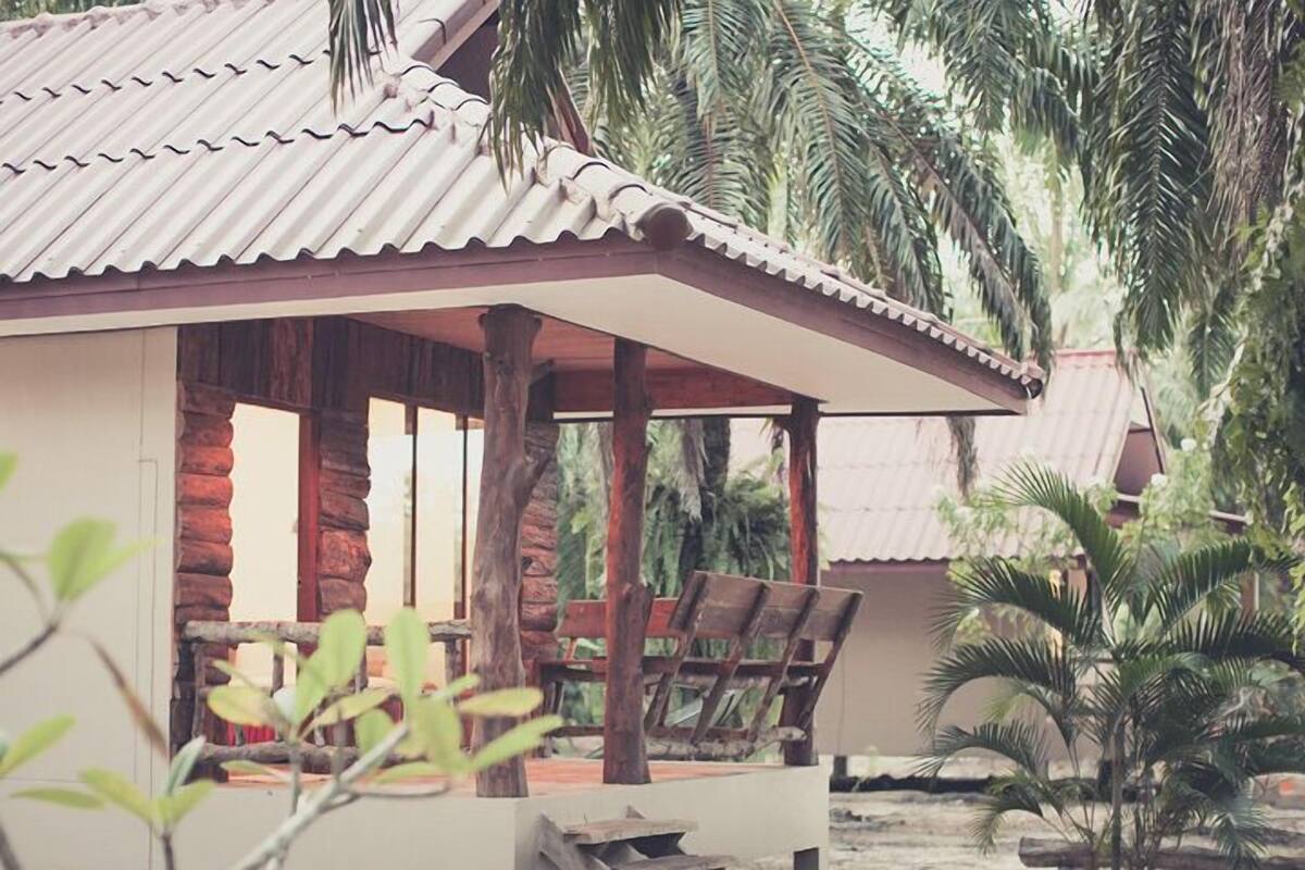 A wooden cabin with a corrugated metal roof, surrounded by palm trees.