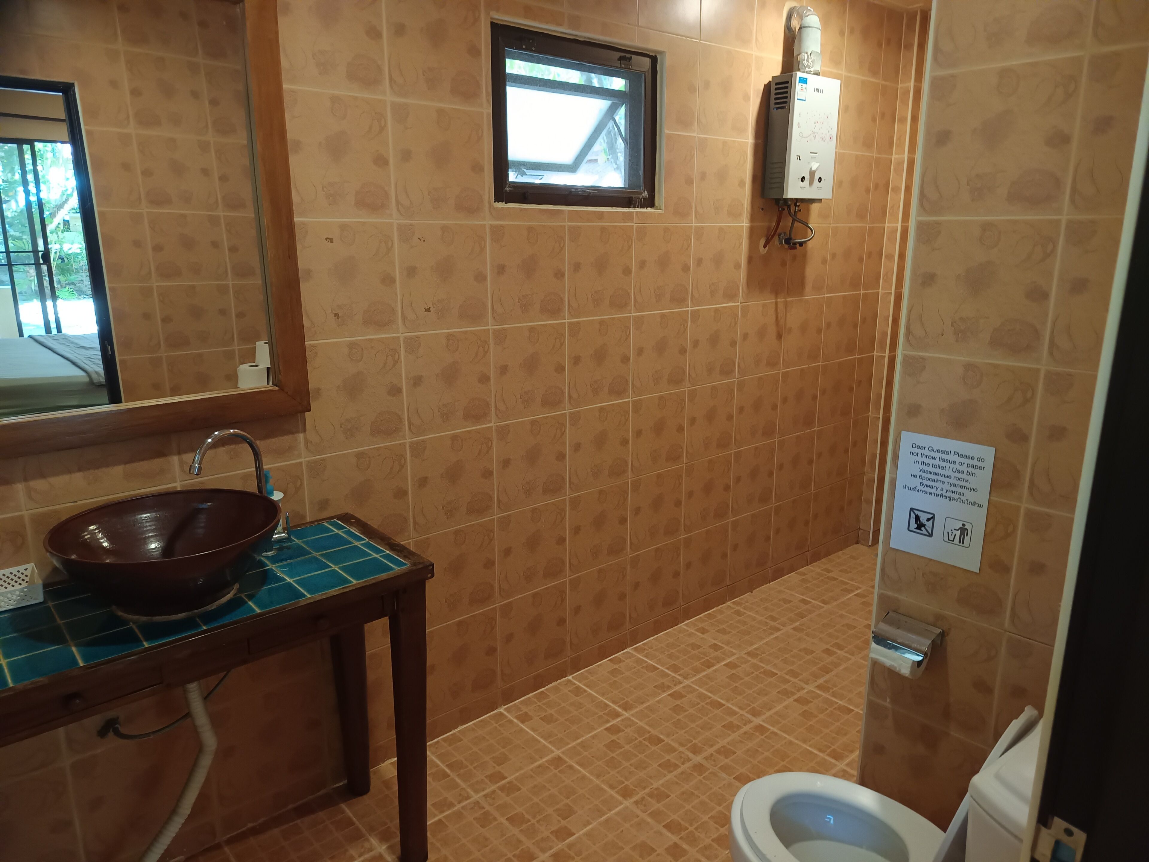 A bathroom with a sink, mirror, window, and toilet.