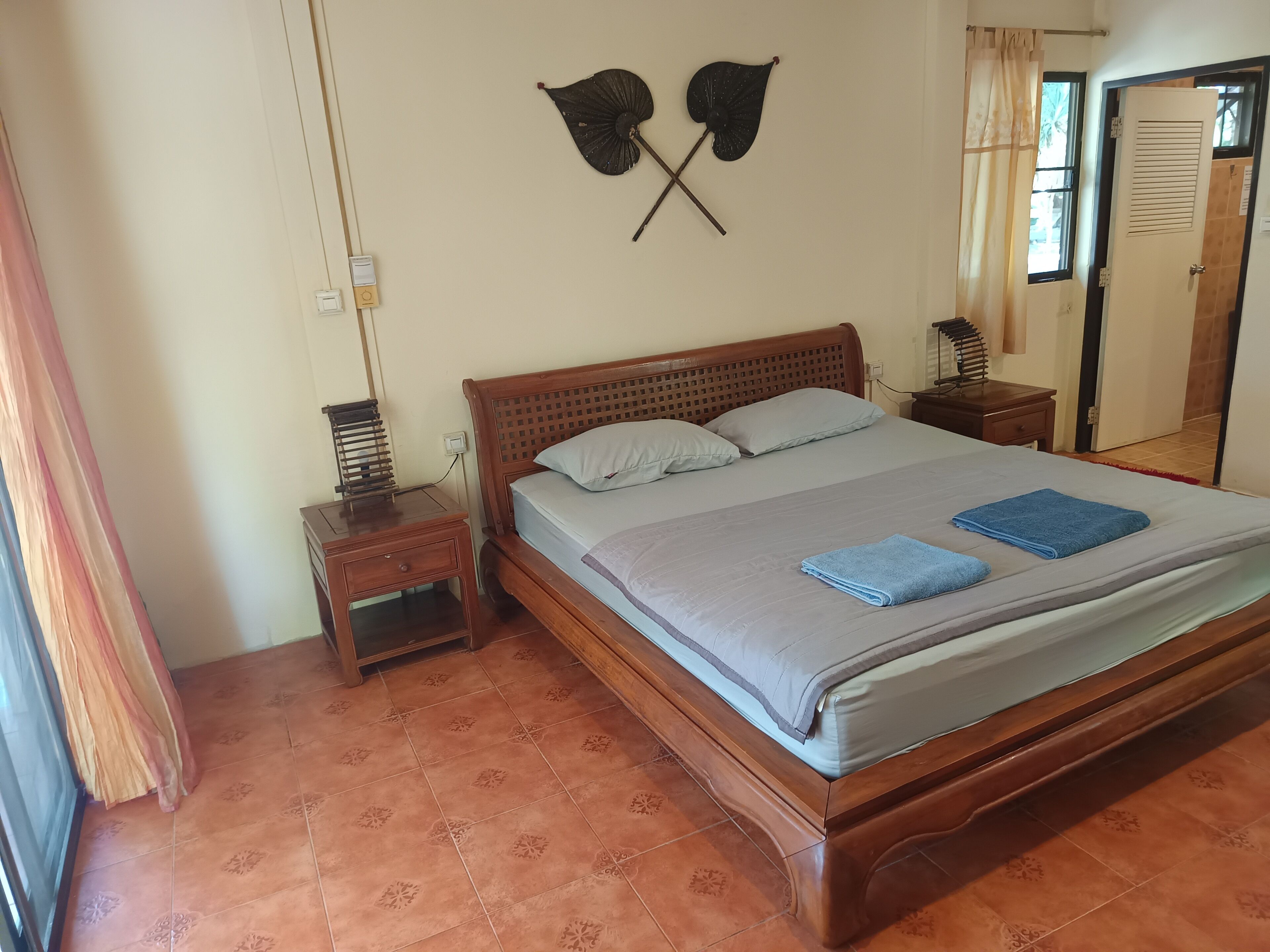 Un dormitorio con cama, mesitas de noche, una lámpara de pared y una puerta.