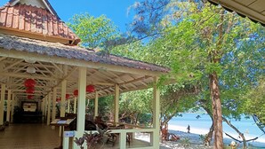A beachside structure with a covered seating area, a view of the beach, and a large tree. - Buffalo Bay Vacation Club (Ranong)