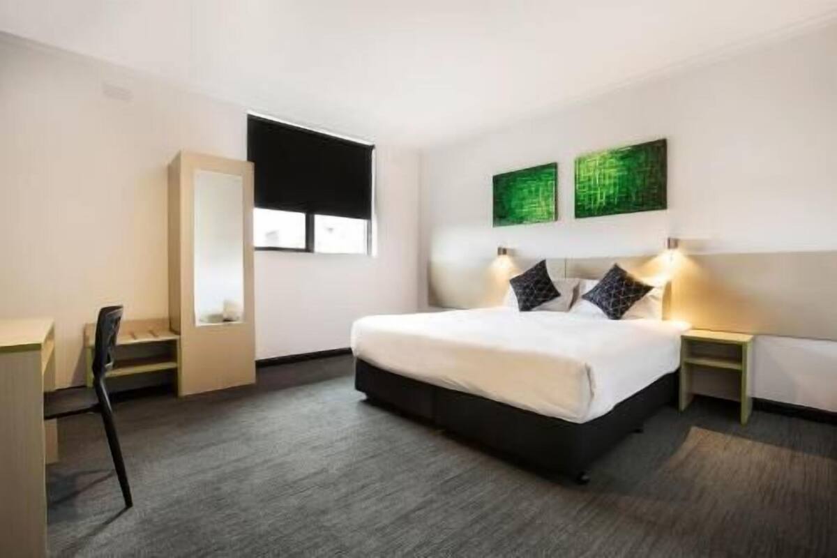 A hotel room with a bed, bedside tables, a desk, and a chair.