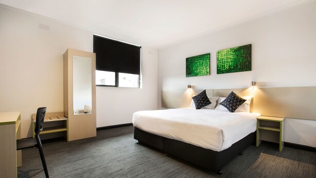 A hotel room with a bed, bedside tables, a desk, a chair, and a window with blinds. - Nightcap at St Albans Hotel (St. Albans)