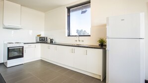 A modern kitchen with white cabinets, a built-in oven, a microwave, and a refrigerator. - Nightcap at St Albans Hotel (St. Albans)