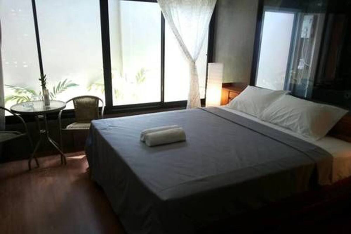 A hotel room with a bed, a small table, and a chair.