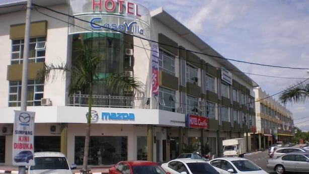 Een hotel genaamd 'Hotel Casavilla' met een Mazda-dealershowroom en een 'Hotel Casavilla' bord op het gebouw.