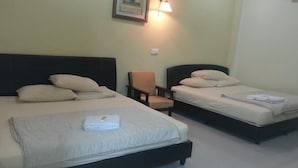 Een hotelkamer met twee bedden, een stoel en een wandlamp.