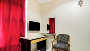 Ein Zimmer mit Schreibtisch, Stuhl, Fernseher und Spiegel.