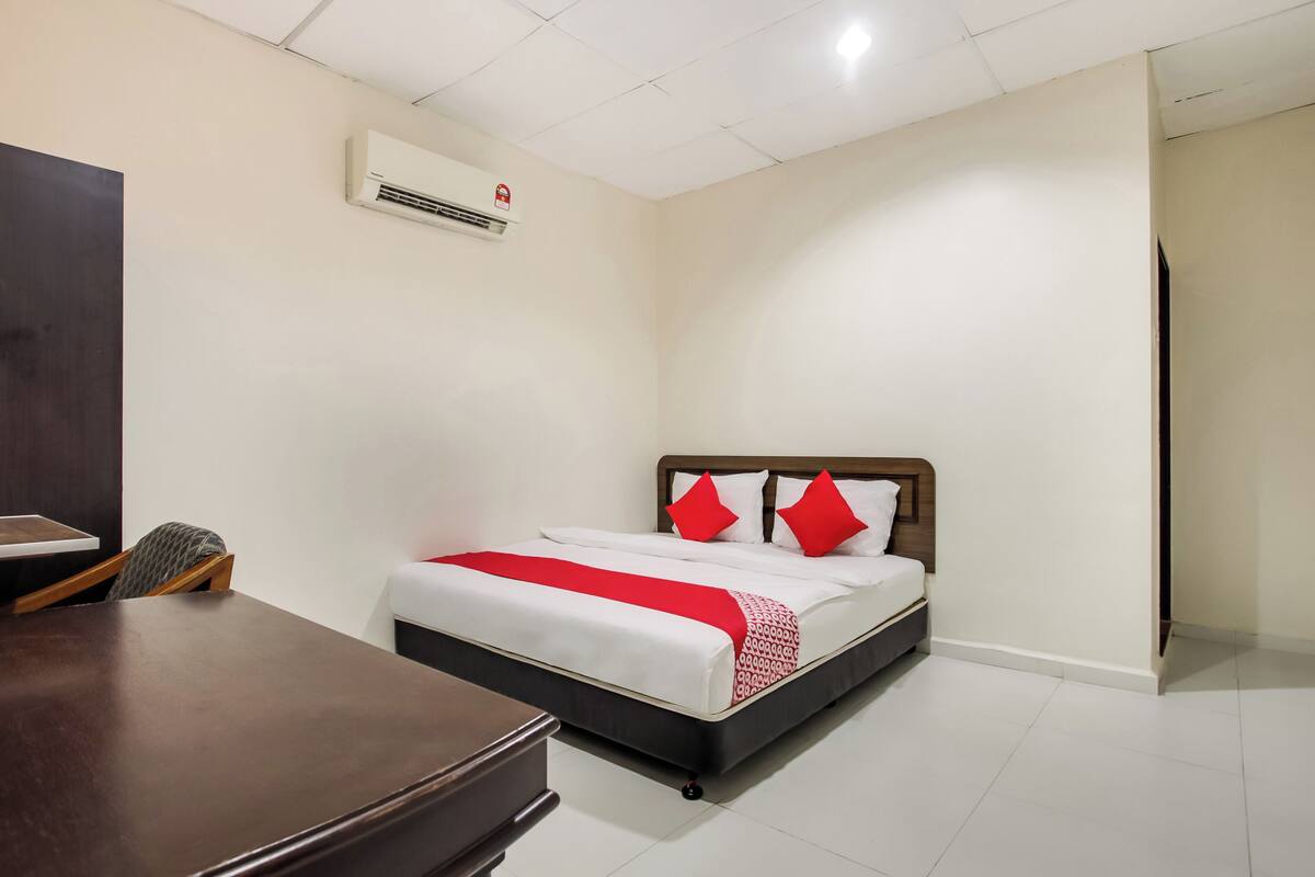 Een hotelkamer met een bed, een bureau, een stoel en een airconditioner aan de muur.