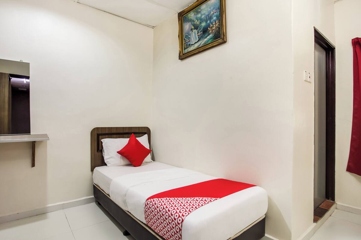Een netjes ingerichte hotelkamer met een bed, een schilderij aan de muur en een deur met gordijn.
