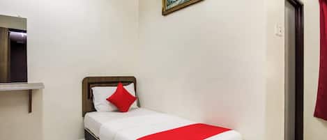 A neatly arranged hotel room with a bed, a painting on the wall, and a door with a curtain.