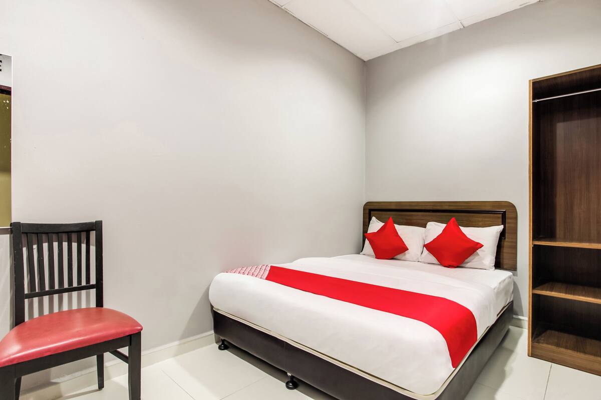 Een keurig opgeruimde slaapkamer met een bed, een stoel en een kledingkast.