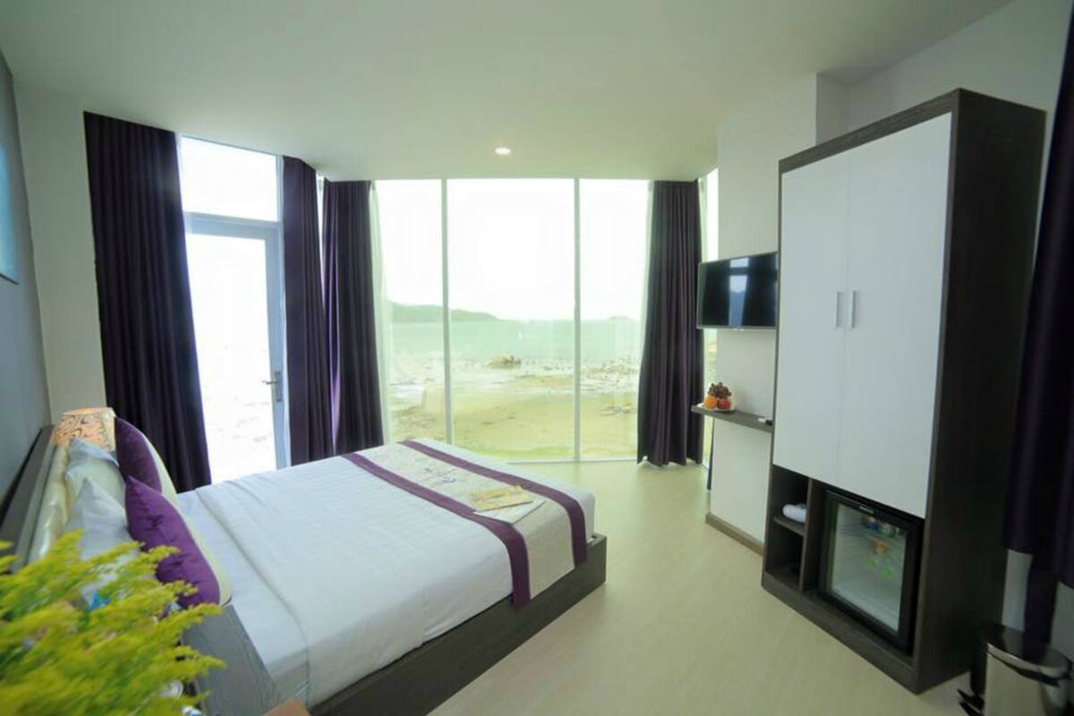 A hotel room with a large bed, a TV, a wardrobe, and a view of the outdoors.