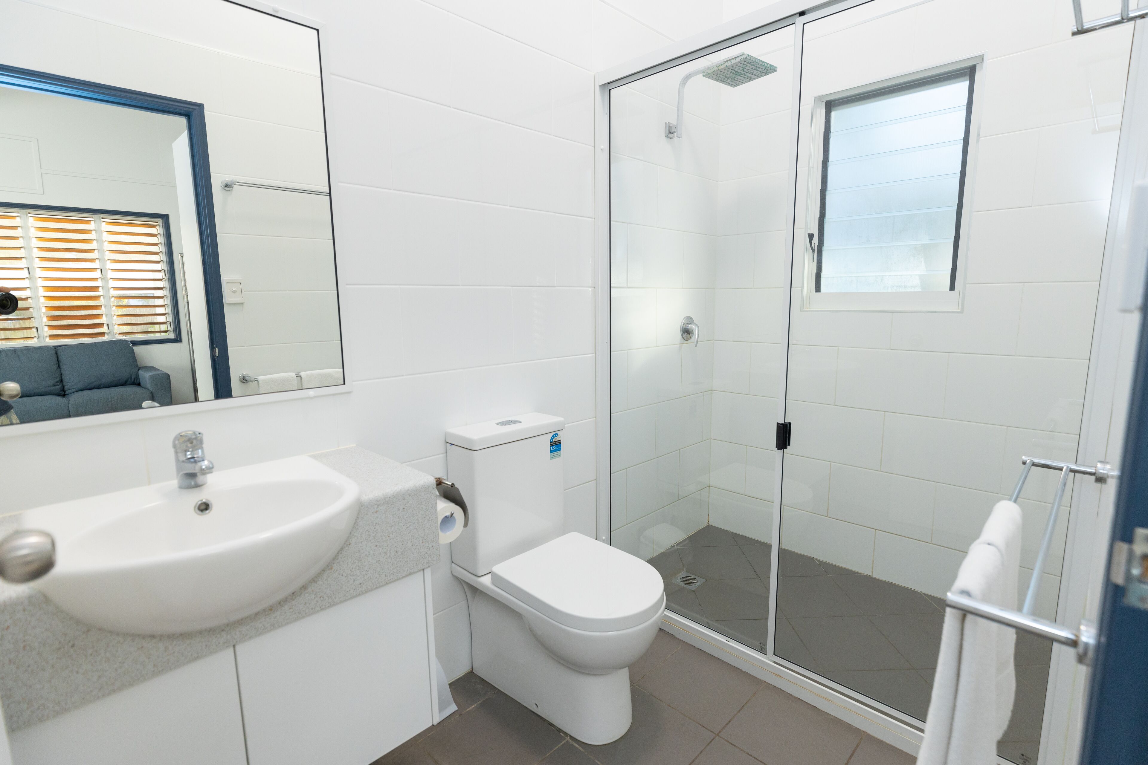 Un baño moderno con lavamanos, inodoro y cabina de ducha de vidrio.