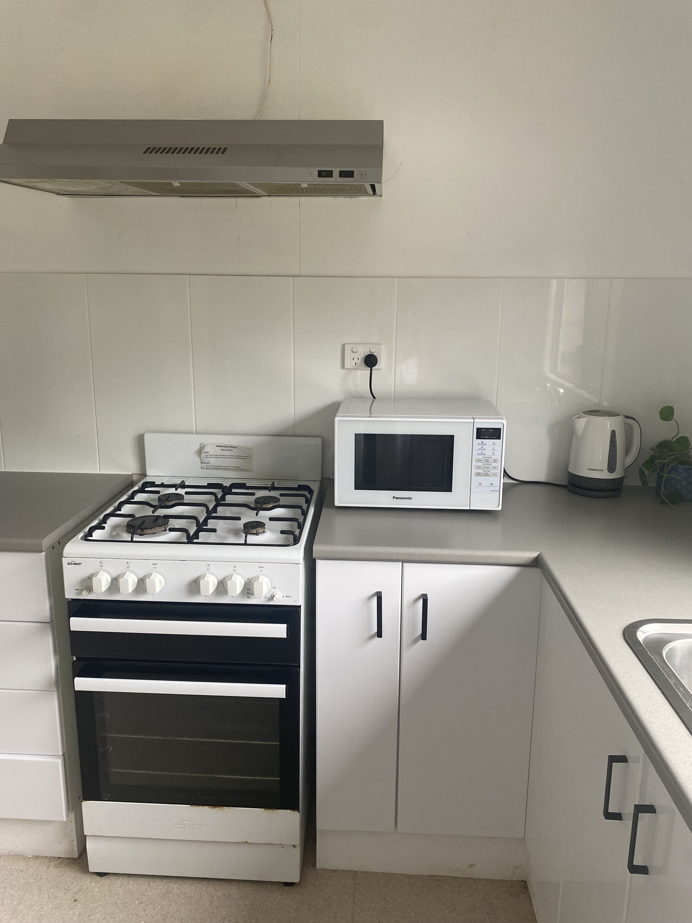 A kitchen with a gas stove, oven, microwave, and cabinets.