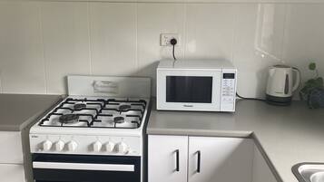 A kitchen with a gas stove, oven, microwave, and cabinets.