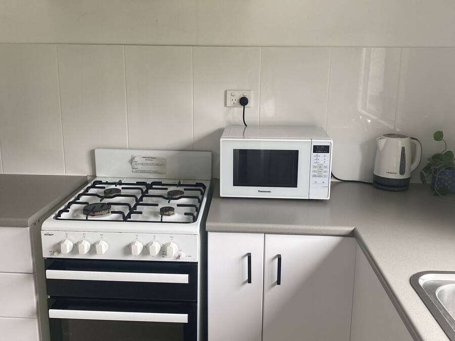 A kitchen with a gas stove, oven, microwave, and cabinets.