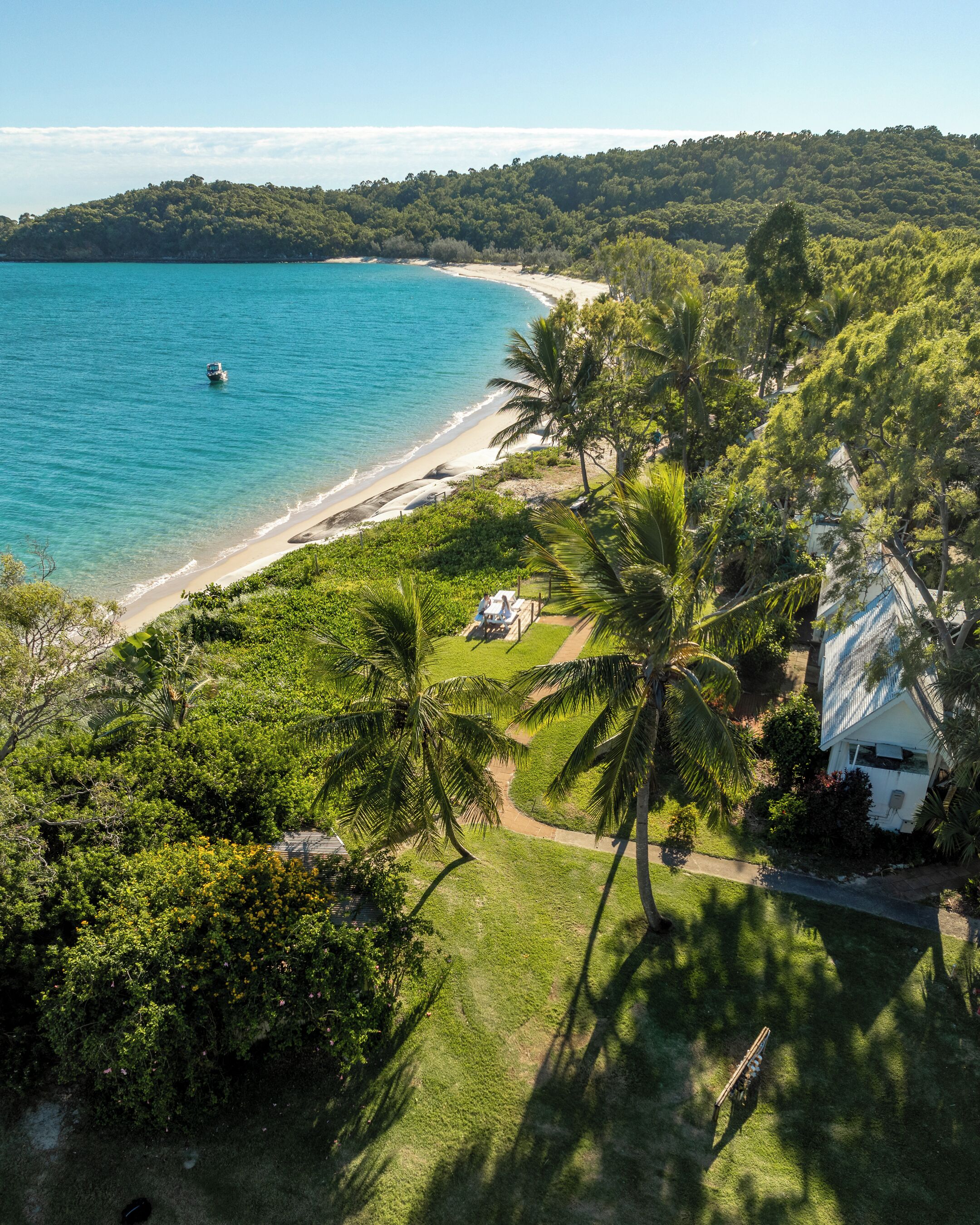 A coastal property with a beach, lush greenery, and a clear view of the ocean.
