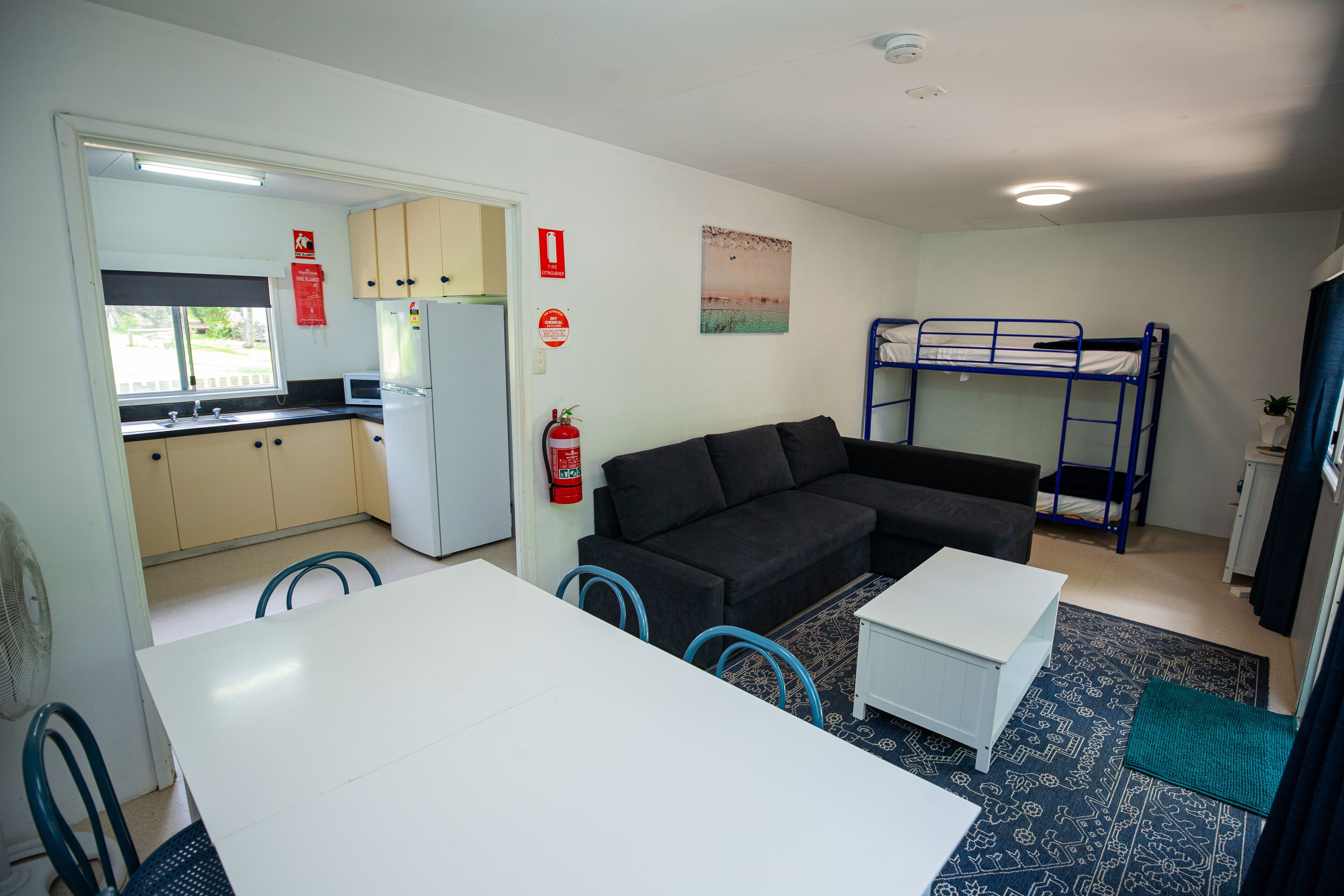 A compact living space with a kitchenette, a sofa, a bunk bed, and a dining area.