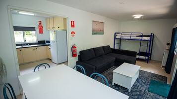 A compact living space with a kitchenette, a sofa, a bunk bed, and a dining area.