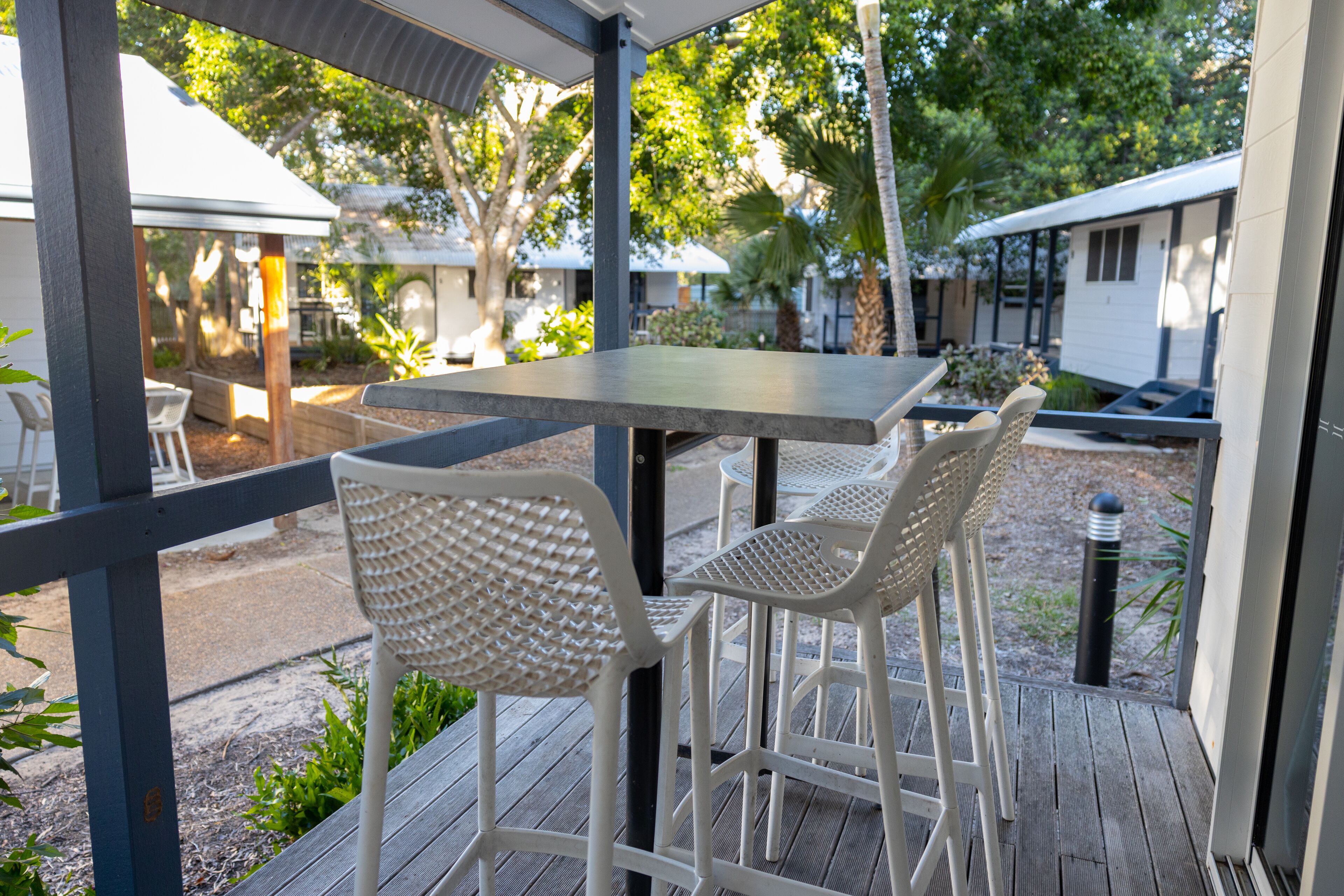 A covered outdoor seating area with a table and two wicker chairs.