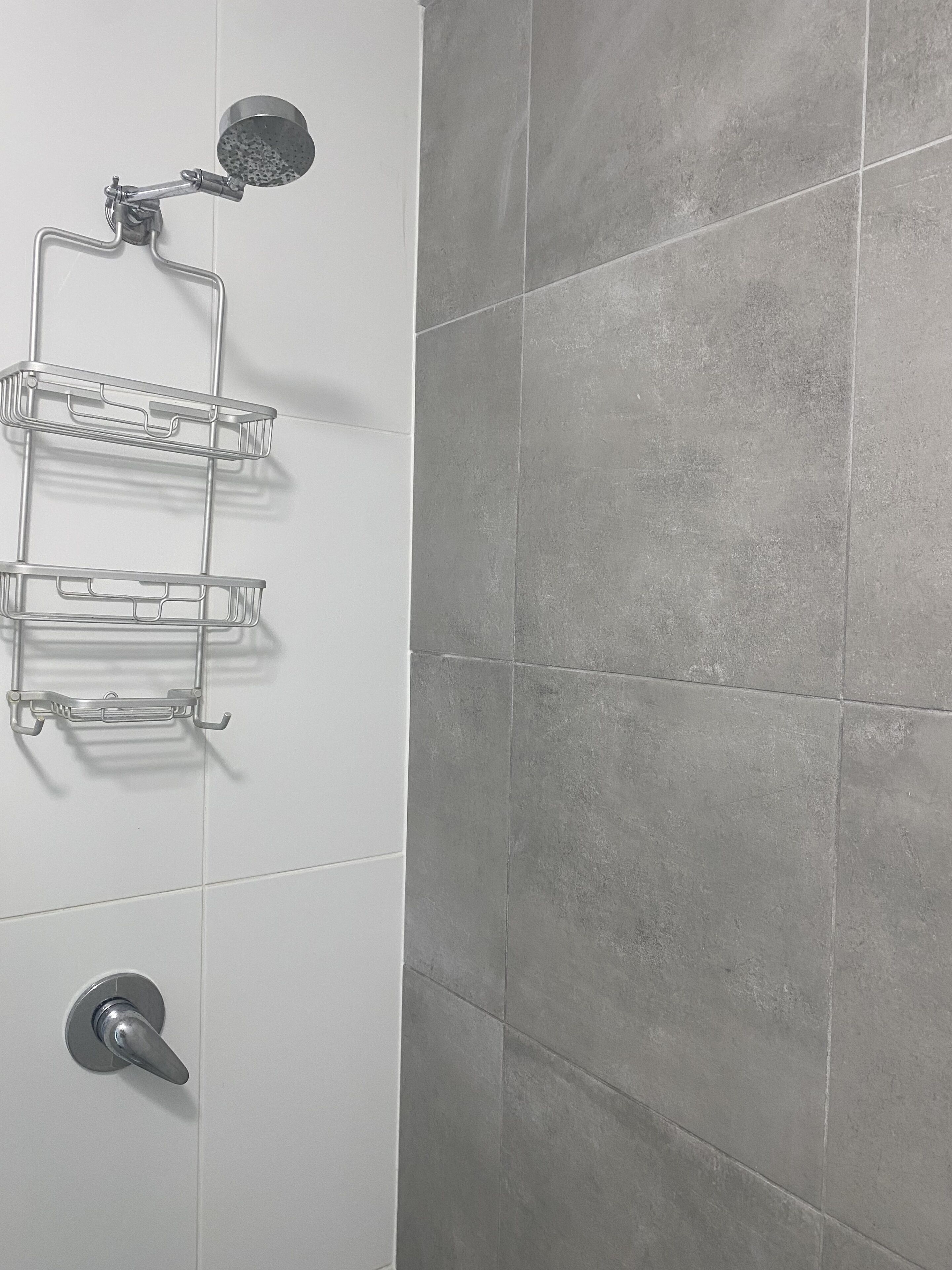 A bathroom with a shower, a metal towel rack, and a toilet.